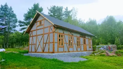 Bilde av et eldhus i bindingsverk i tradisjonell stil. Omringet av skog