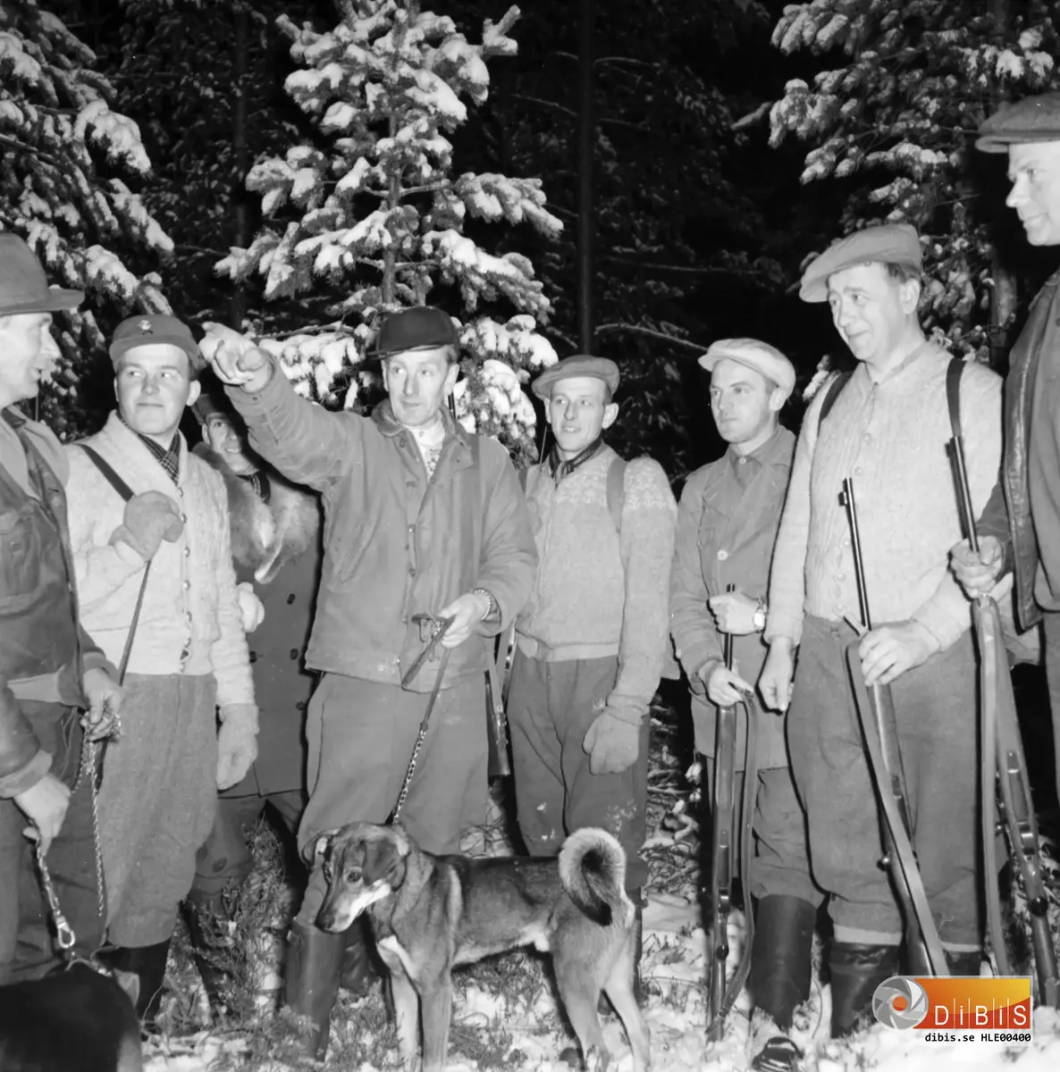 Älgjakt i Våsbo, skyttar ställs ut. 
Fr. h.: Olors Julle - Julius Olols Lunds Gottfrid Voxberg, Lassas Elias Eriksson, Gösta Vennberg, Henning Östergårds, Koppars Ivar Mårtensson Okänd till vänster.