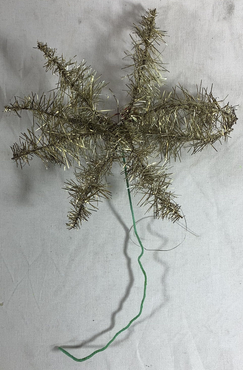 Fem julepyntede stjerner, sannsynligvis beregnet for plassering på toppen av et juletre. Hver stjerne er formet av metalltråd innpakket i sølvfarget glitterdekor, med noen som har små røde kuler som ekstra pynt. Glitteret gir en strålende og festlig effekt, selv om noen av stjernene har tegn til slitasje med deler av glitteret som er borte, og stjerneformene er noe deformert. 

