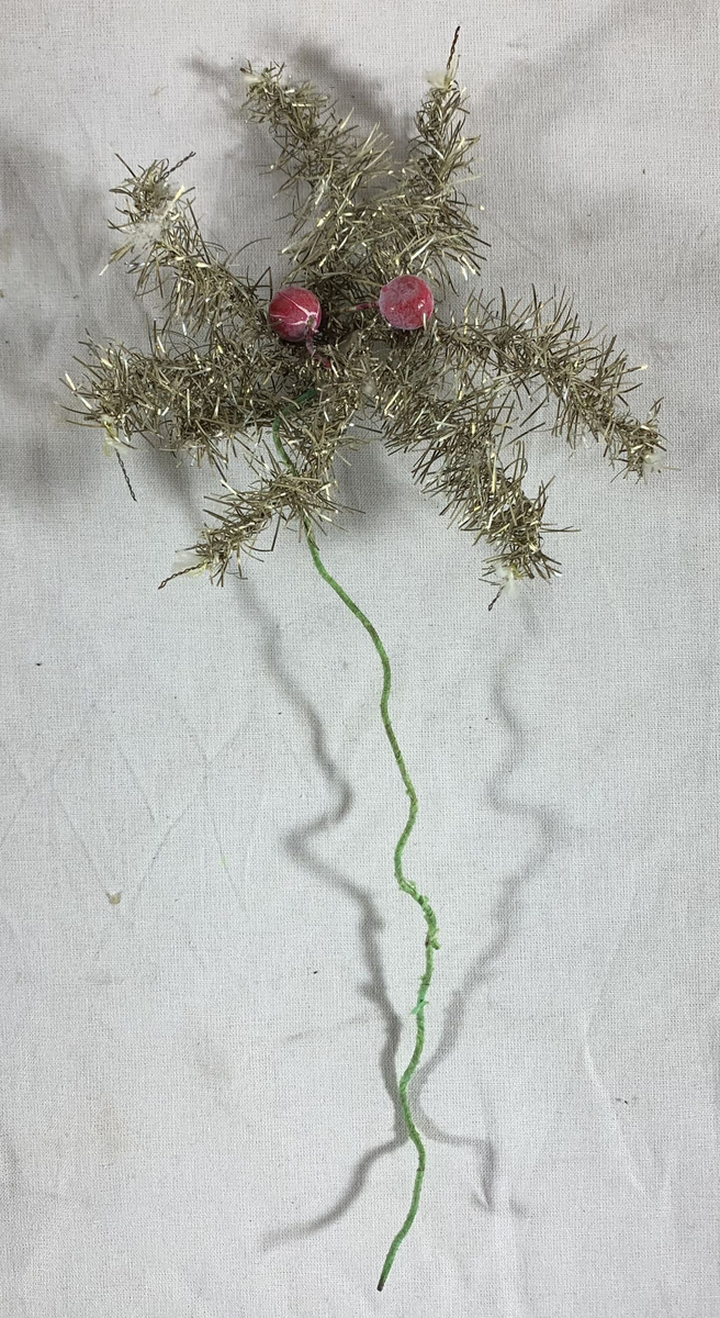 Fem julepyntede stjerner, sannsynligvis beregnet for plassering på toppen av et juletre. Hver stjerne er formet av metalltråd innpakket i sølvfarget glitterdekor, med noen som har små røde kuler som ekstra pynt. Glitteret gir en strålende og festlig effekt, selv om noen av stjernene har tegn til slitasje med deler av glitteret som er borte, og stjerneformene er noe deformert. 

