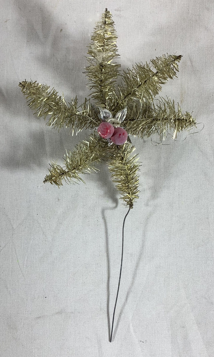 Fem julepyntede stjerner, sannsynligvis beregnet for plassering på toppen av et juletre. Hver stjerne er formet av metalltråd innpakket i sølvfarget glitterdekor, med noen som har små røde kuler som ekstra pynt. Glitteret gir en strålende og festlig effekt, selv om noen av stjernene har tegn til slitasje med deler av glitteret som er borte, og stjerneformene er noe deformert. 

