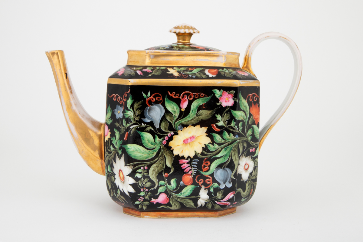 Kaffekanne i glasert porselen med polykrom blomsterdekor på svart bunn og forgylte kanter, tut, lokknapp og hank. Kannen har firkantet form med avfasede hjørner.