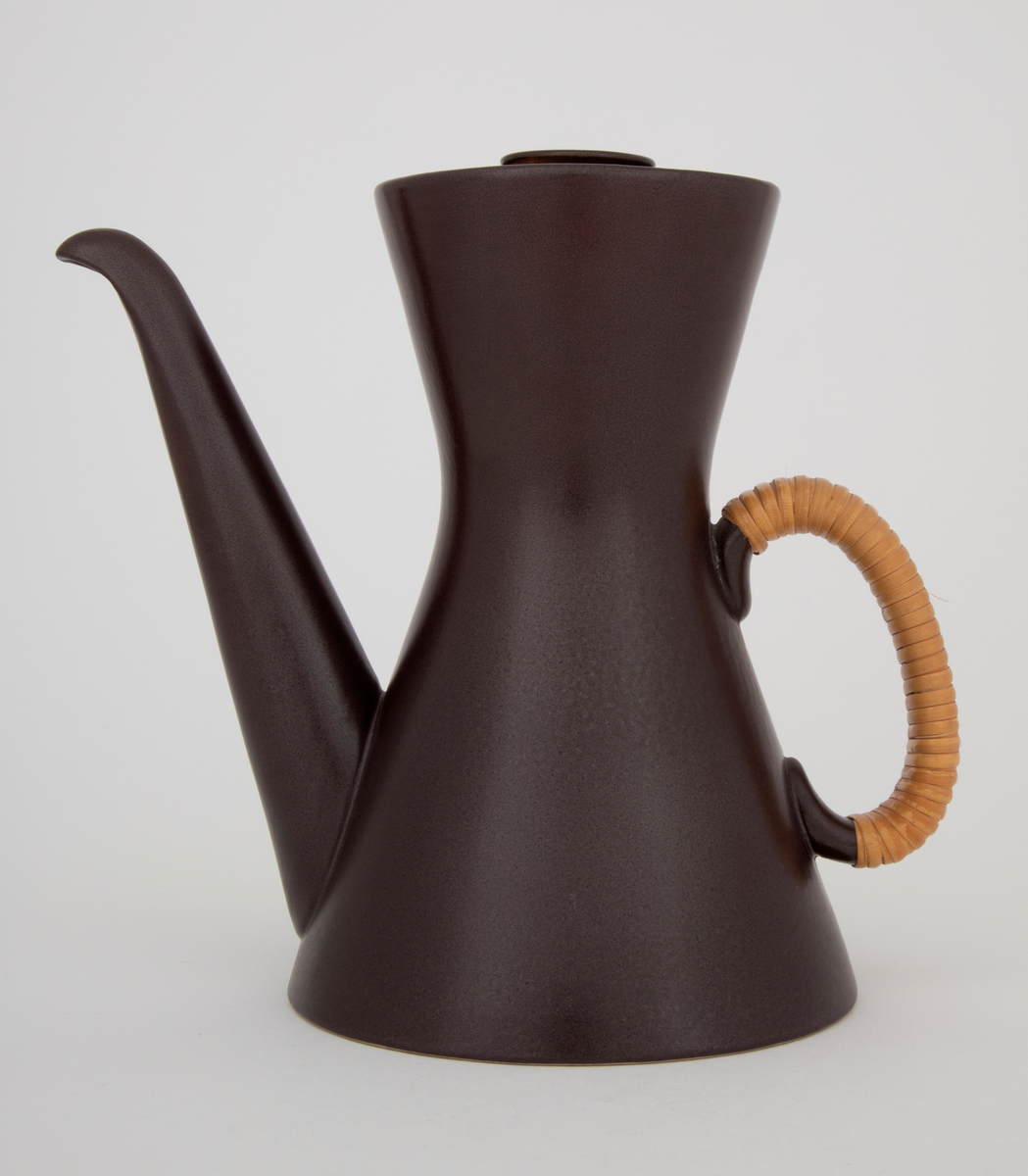 Kaffekanne med lokk i glasert plate- og ovnsfast steingods (novarlitt). Kannen har timeglassform, lang tut og peddigomviklet hank. Mørk sjokoladebrun farge med matt glasur. Bunnen er uglasert.