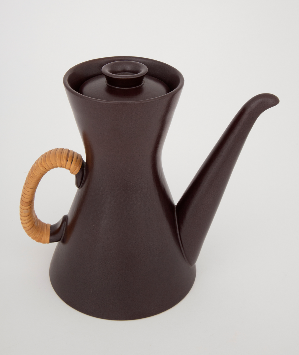 Kaffekanne med lokk i glasert plate- og ovnsfast steingods (novarlitt). Kannen har timeglassform, lang tut og peddigomviklet hank. Mørk sjokoladebrun farge med matt glasur. Bunnen er uglasert.