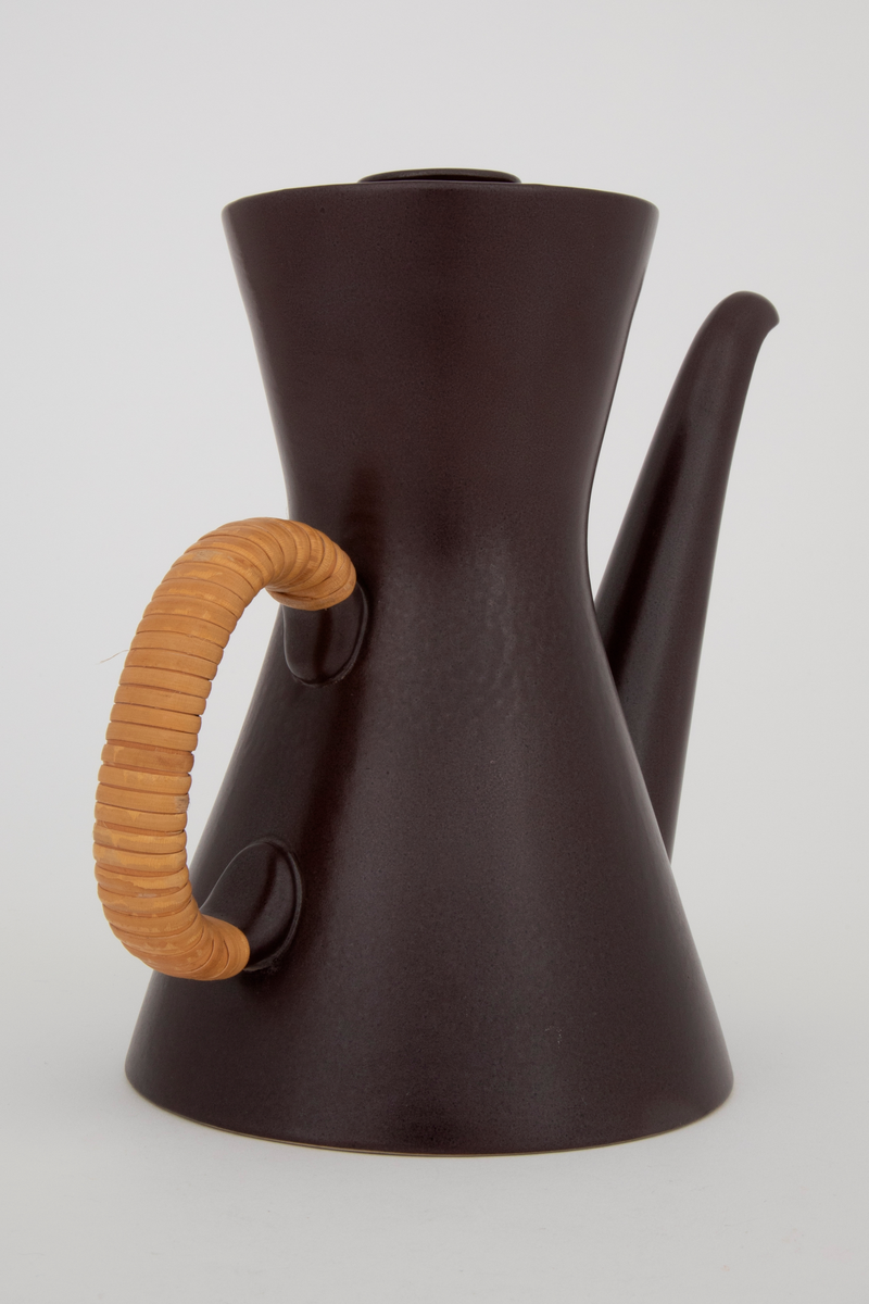 Kaffekanne med lokk i glasert plate- og ovnsfast steingods (novarlitt). Kannen har timeglassform, lang tut og peddigomviklet hank. Mørk sjokoladebrun farge med matt glasur. Bunnen er uglasert.