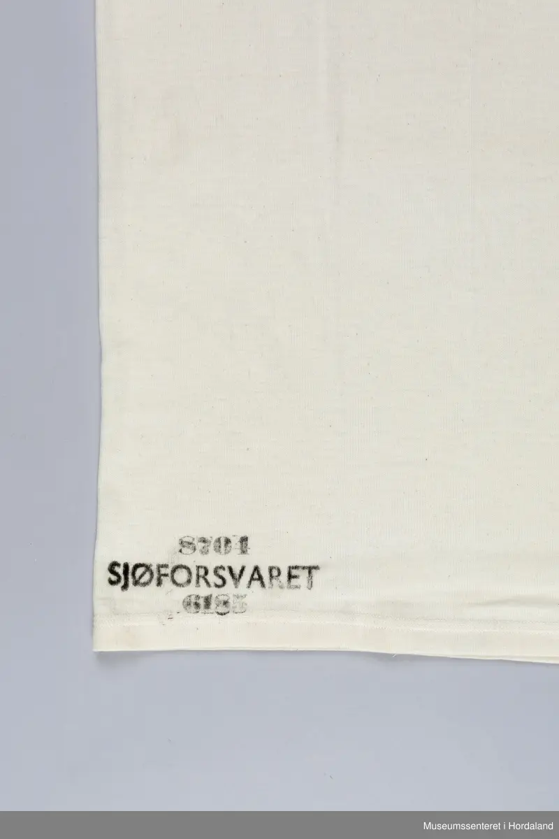Trøye uten erm, "singlet", undertøy til menn. Industristrikk produsert for Sjøforsvaret: trøya er merka "8704 Sjøforsvaret 6185".