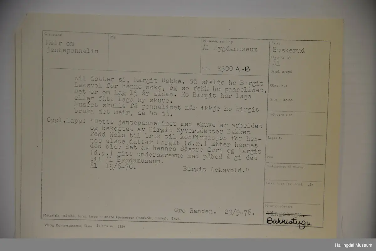 a) Jentepannelin av papp, sylkjety, bolu, kårilsteinar, bomullsty, ullgarn, sydd.
b) Nakkeskuve av flanillsgarn i raudt, mørk raudt, lys raudt, kvitt, lys gult, og grønt.