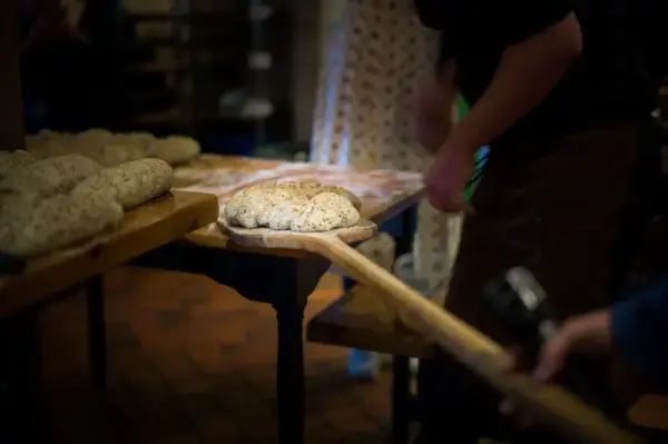 brødbaking. Brødene løftes inn i ovnen. 