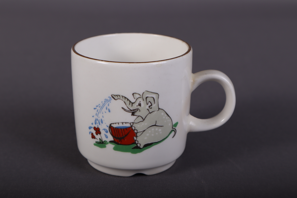 Liten hvit kopp med trykt dekor som viser elefant med paraply på den ene siden og elefant som vanner blomster på den andre siden.