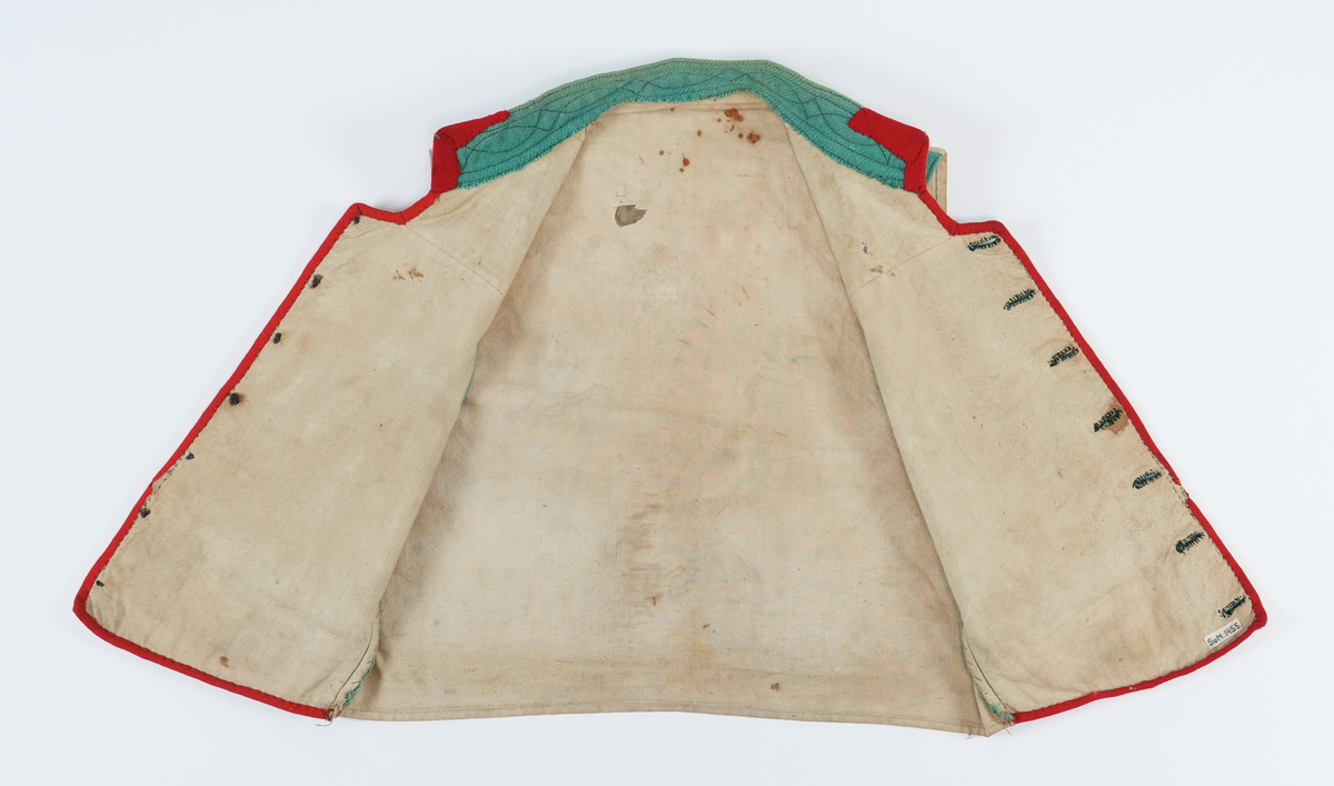 Vest med høg dobbellagd krage, med brune stikningar. Ein liten rund opning mellom kragen og kneppinga. Enkel knapperad, 7 "matrosknappar", det nederste knappet er litt anneledes fra de andre. Avrunda i framkant. Stikklomme med stolpeklaff på kvar side. Framstykka er fora, same stoffet er brukt som bakstykke. Opning og lommekaffar kanta med raude mohairband.