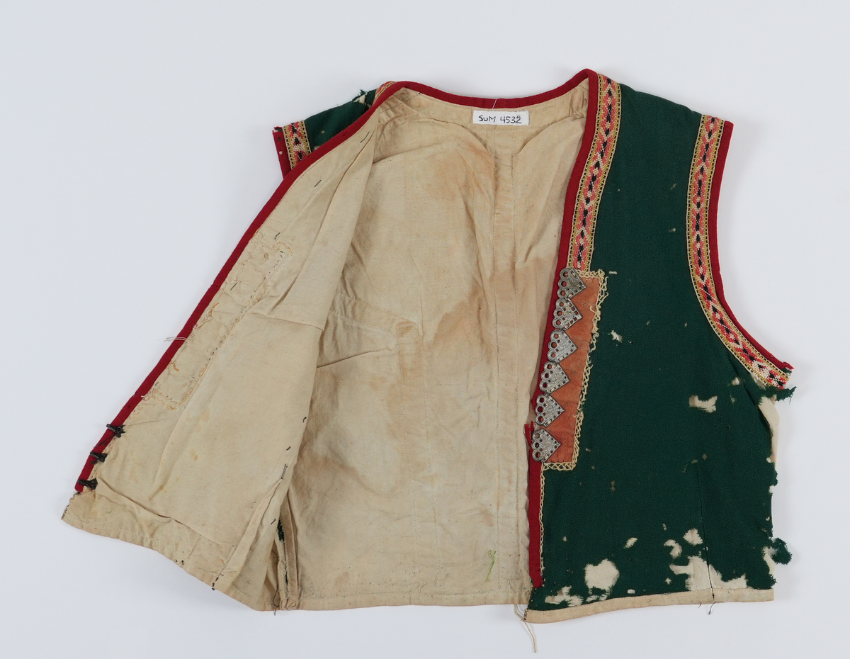 Livstykket har V-opning med maljedukar kanta med broderi. På begge side er det 6 maljer med tre auge på kvar. Kvarding av raud ull rundt alle opningane, innafor desse grindvovne band. Under maljsklutane er banda erstatta med broderte kjedsting. Fora med ubleika lerret.
