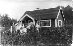 Vykort med en grupp vuxna och barn som står framför en liten