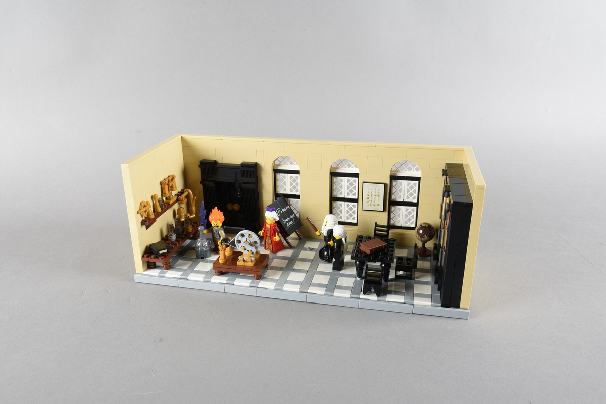 Tablået er bygget av Lego i diverse farger. Scene med fire mennesker i et laboratorium. Leiden, vinteren 1759, Pieter van Musschenbroeks laboratorium.