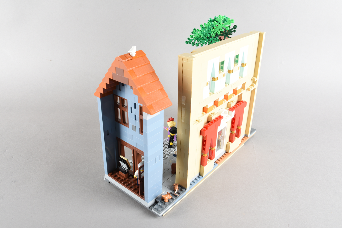 Tablået er bygget av Lego i diverse farger. Scene med syv mennsker stående, gående og sittende utenfor en cafè og bokhandel. Wien 1870, Cafe Hochleitner.