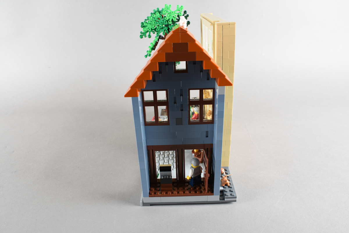 Tablået er bygget av Lego i diverse farger. Scene med syv mennsker stående, gående og sittende utenfor en cafè og bokhandel. Wien 1870, Cafe Hochleitner.