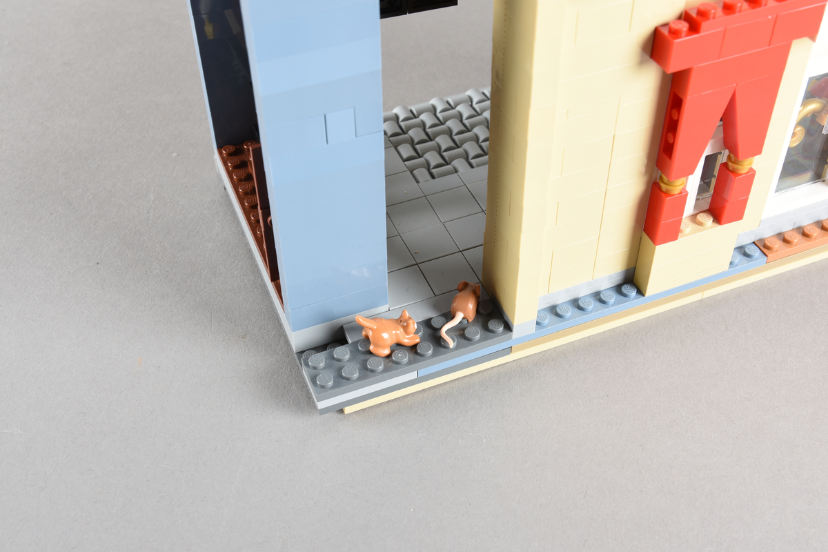 Tablået er bygget av Lego i diverse farger. Scene med syv mennsker stående, gående og sittende utenfor en cafè og bokhandel. Wien 1870, Cafe Hochleitner.