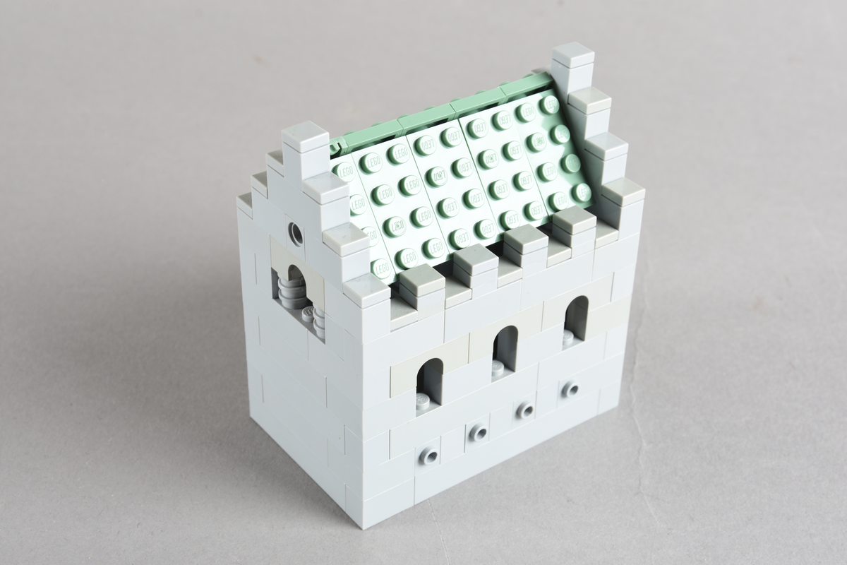 Mikrobygg bestående av lego. Ingen innmat i bygget, kun skallet. Skallet er bygget av grå middels og små legoklosser, med buede åpninger og løst tak. Taket er grønt. Endeveggene har buet åpning høyt på veggen, og en rundt liten åpning med en rød legokloss på innsiden for å imitere et vindu.