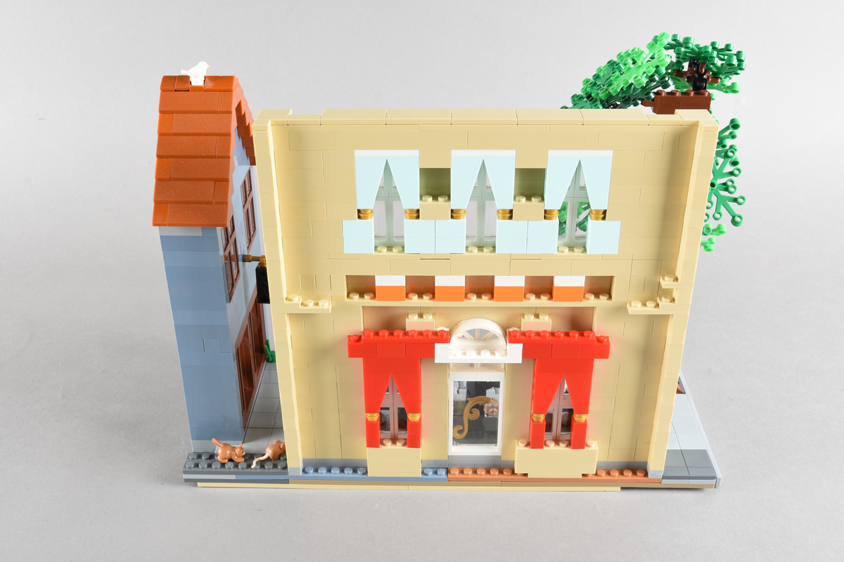 Tablået er bygget av Lego i diverse farger. Scene med syv mennsker stående, gående og sittende utenfor en cafè og bokhandel. Wien 1870, Cafe Hochleitner.