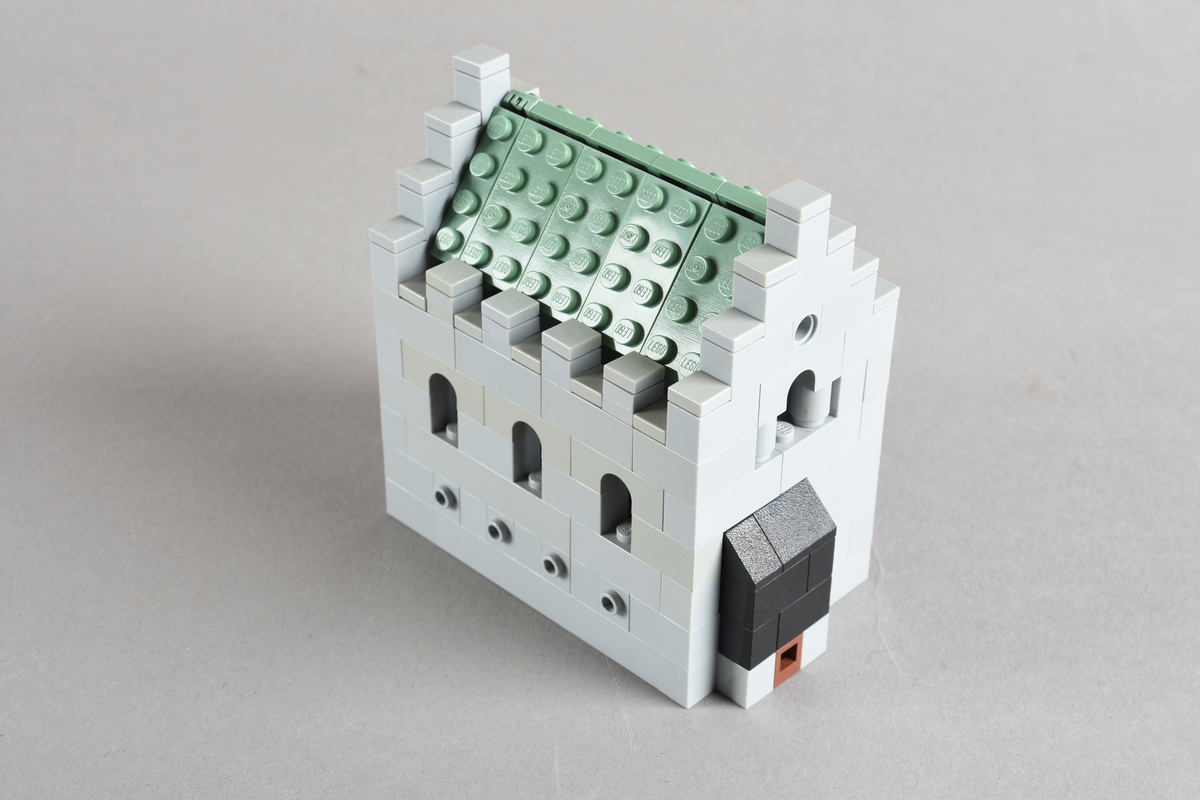 Mikrobygg bestående av lego. Ingen innmat i bygget, kun skallet. Skallet er bygget av grå middels og små legoklosser, med buede åpninger og løst tak. Taket er grønt. Endeveggene har buet åpning høyt på veggen, og en rundt liten åpning med en rød legokloss på innsiden for å imitere et vindu.
