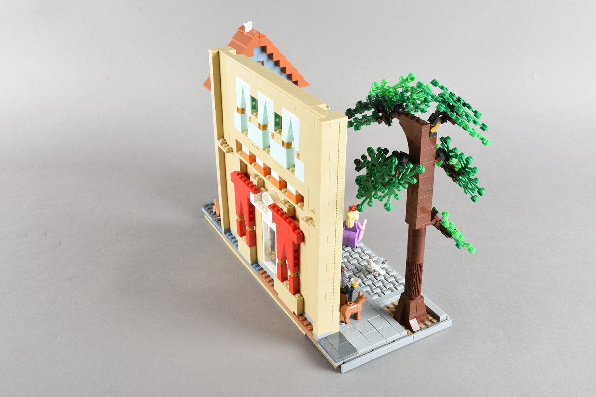 Tablået er bygget av Lego i diverse farger. Scene med syv mennsker stående, gående og sittende utenfor en cafè og bokhandel. Wien 1870, Cafe Hochleitner.
