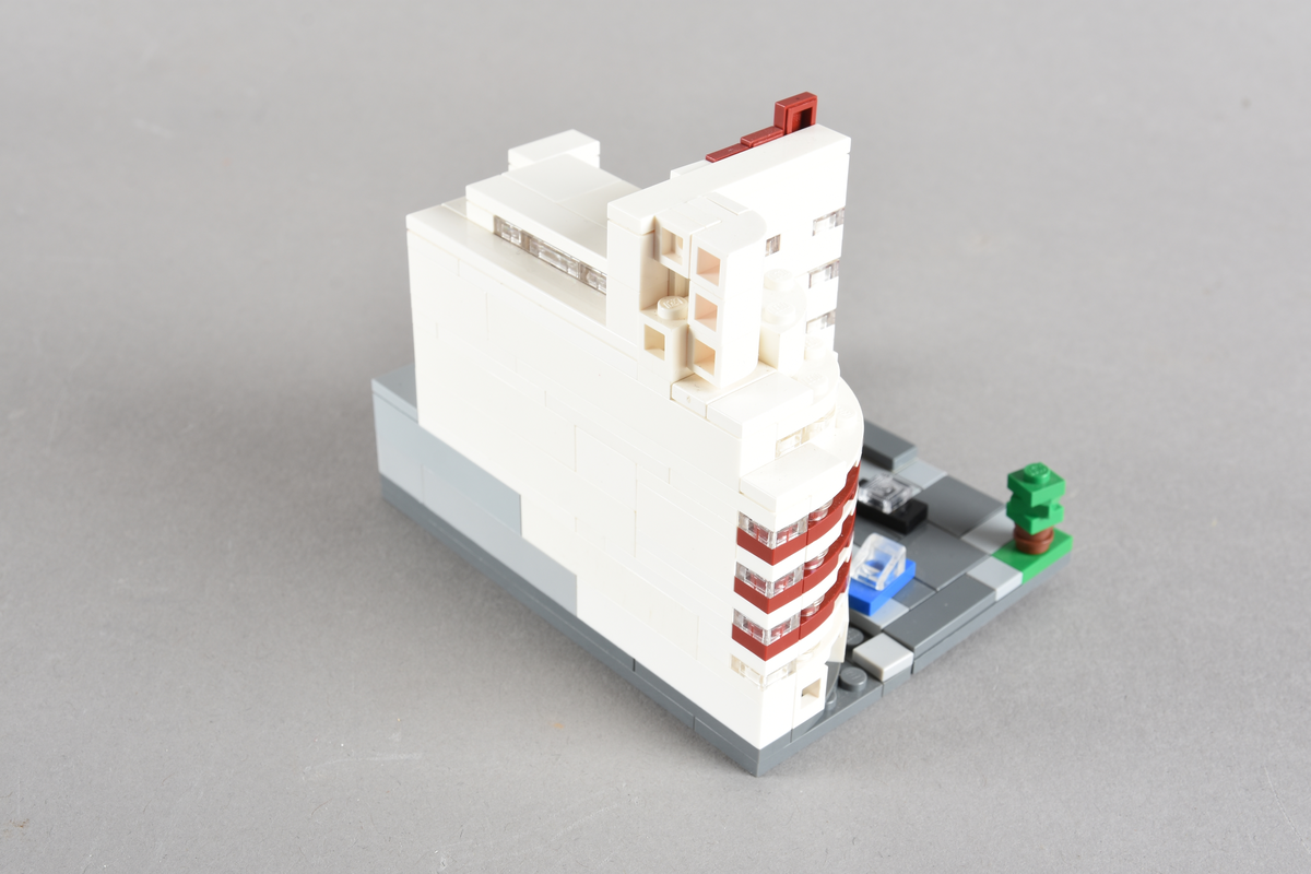 Mikrobygg bestående av lego. Tett bygg i hvitt og rødbrunt, med gateplan i grått. Biler på gateplan i rød, gul, sort og blå.