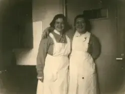 Två kvinnliga sjukvårdsbiträden står i ett rum och håller om