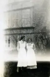 Två sjukvårdsbiträden står på en gräsmatta och håller om var