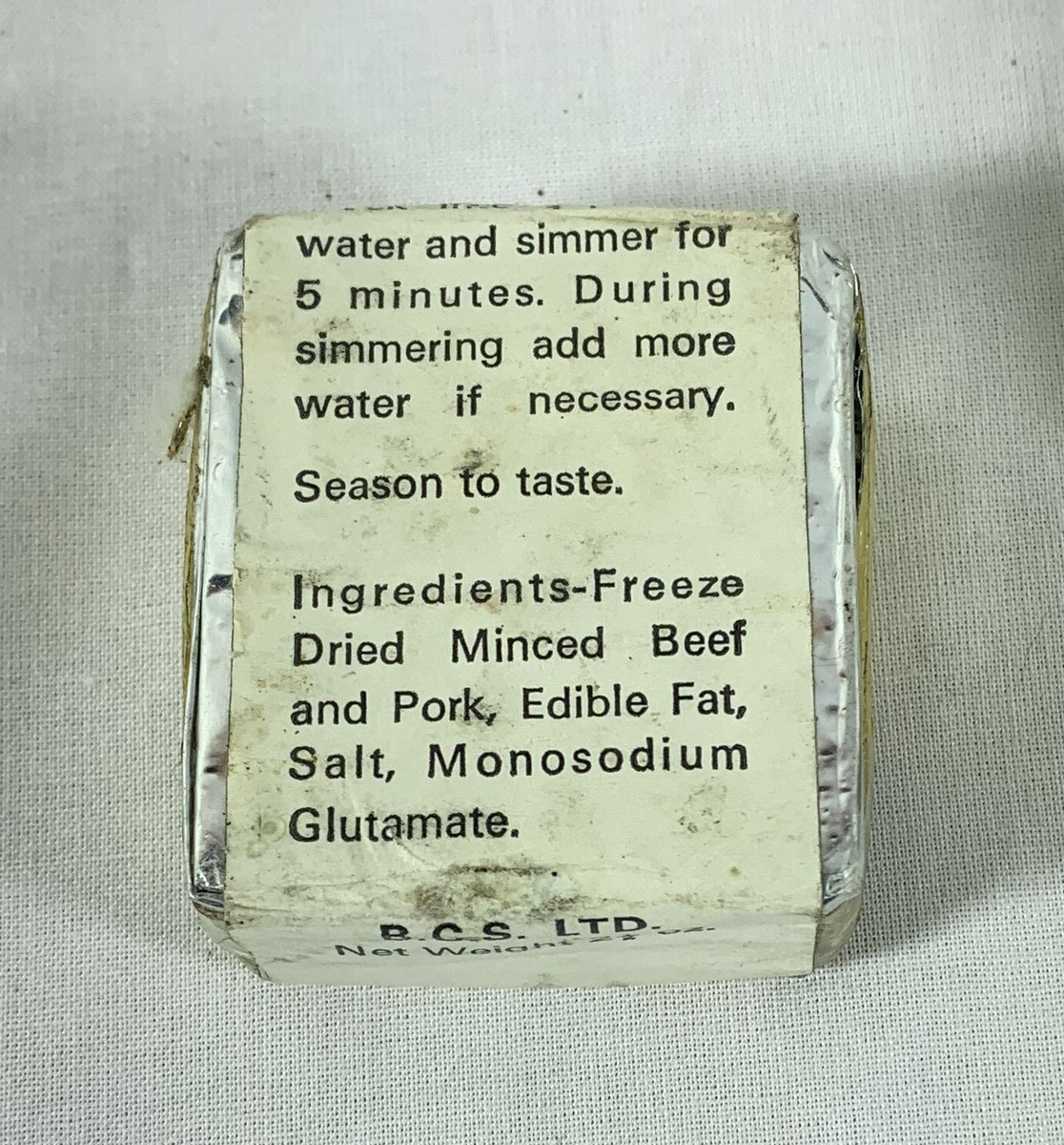 Firkantet blokk merket "Beef and Pork Bar" pakket inn i folie med hvit papiretikett. Foran står det at innholdet tilsvarer omtrent 7 ½ oz. rå benfritt kjøtt, og at kjøttbaren kan brukes til gryteretter eller suppe. På baksiden oppgis ingrediensene som frysetørket, malt okse- og svinekjøtt, spiselig fett, salt og mononatriumglutamat. Instruksjonene nevner å koke kjøttet i vann i fem minutter, med mulighet for å tilsette mer vann under kokingen.














