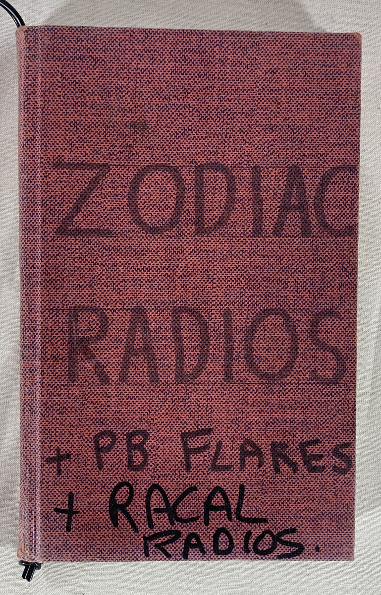 Loggbok, innbundet i et rødt omslag med påskriften "ZODIAC RADIOS + PB FLARES + RACAL RADIOS" på forsiden. Inneholder dokumentasjon av reparasjoner og bruk av forskjellige radioutstyr fra 1974 til 1983. Den inneholder detaljer om radioutstyr som har vært brukt av ulike team, med notater om problemer som defekte knapper, vanndamage og strømbrytere som trengte reparasjon. På baksiden av loggboken er det ingen tekst bortsett fra merket "Collins IDEAL 441" trykt i gull.