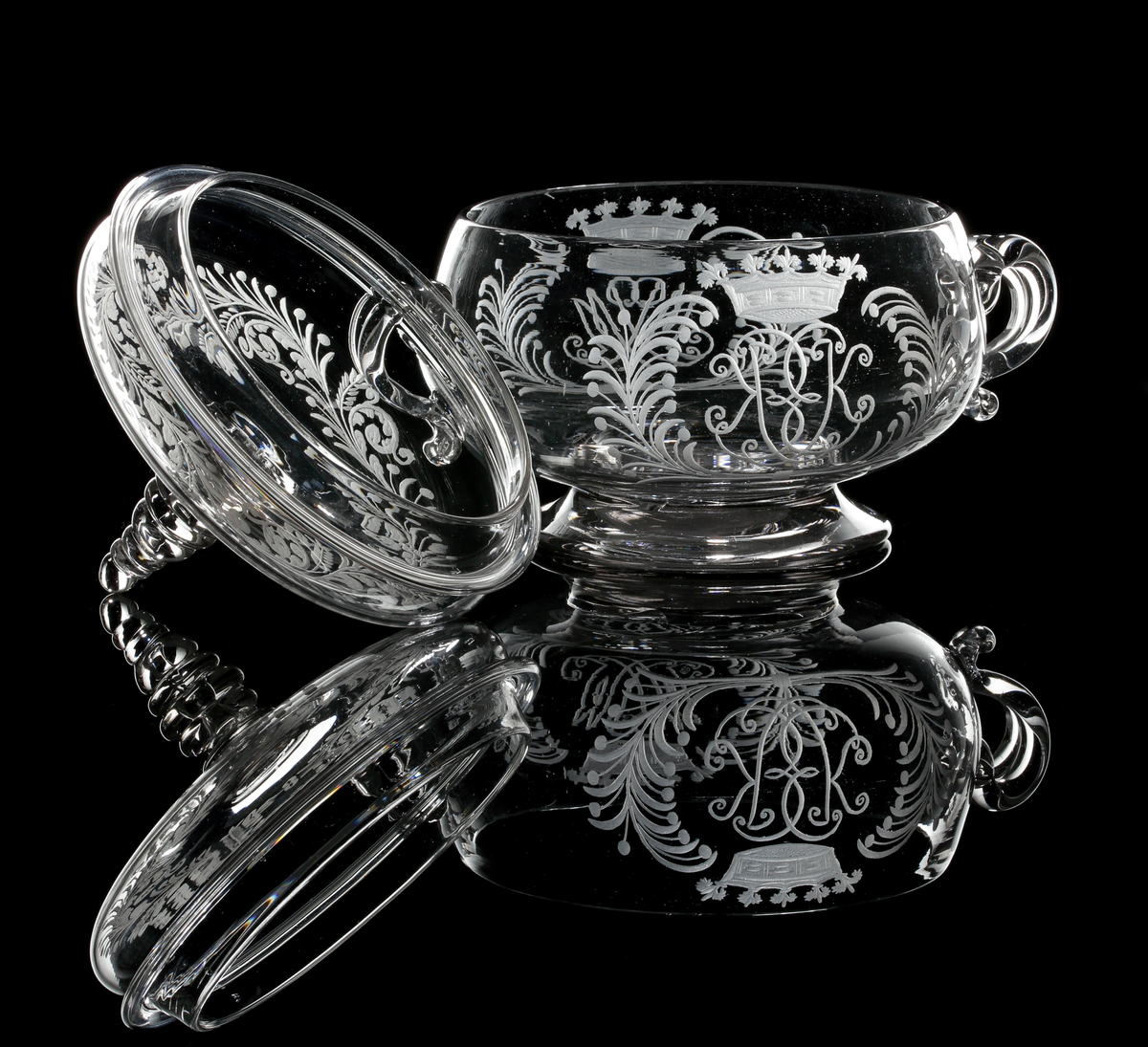 Smörask bestående av skål med två hänklar och lock med profilerad knopp.
På vardera motsatt sida graverade monogram med initialerna "M.P" och "E.K" under grevlig krona, flankerade av palm- och bärkvistar.
Bladranka på locket.
Inskriven i huvudkatalogen efter mars 1997.

Litteratur:
Se Seitz "Äldre Svenska glas", bild 51, Skånska glasbruket