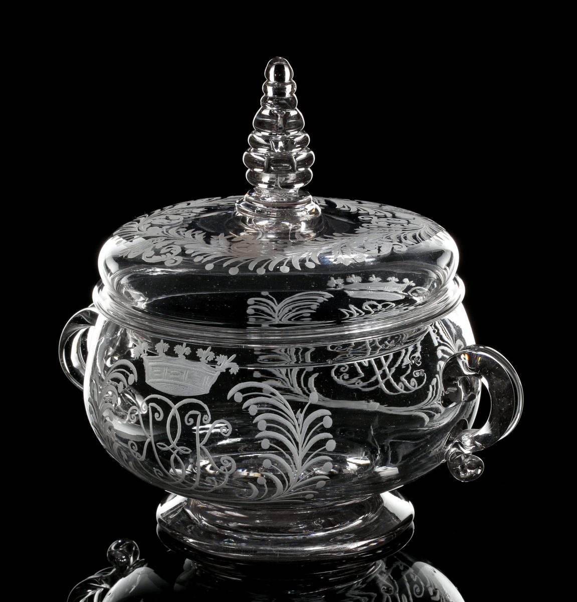 Smörask bestående av skål med två hänklar och lock med profilerad knopp.
På vardera motsatt sida graverade monogram med initialerna "M.P" och "E.K" under grevlig krona, flankerade av palm- och bärkvistar.
Bladranka på locket.
Inskriven i huvudkatalogen efter mars 1997.

Litteratur:
Se Seitz "Äldre Svenska glas", bild 51, Skånska glasbruket