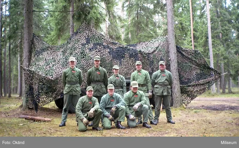 Värnpliktiga. Maskerad Terrängbil 30 Scania i bakgrunden.