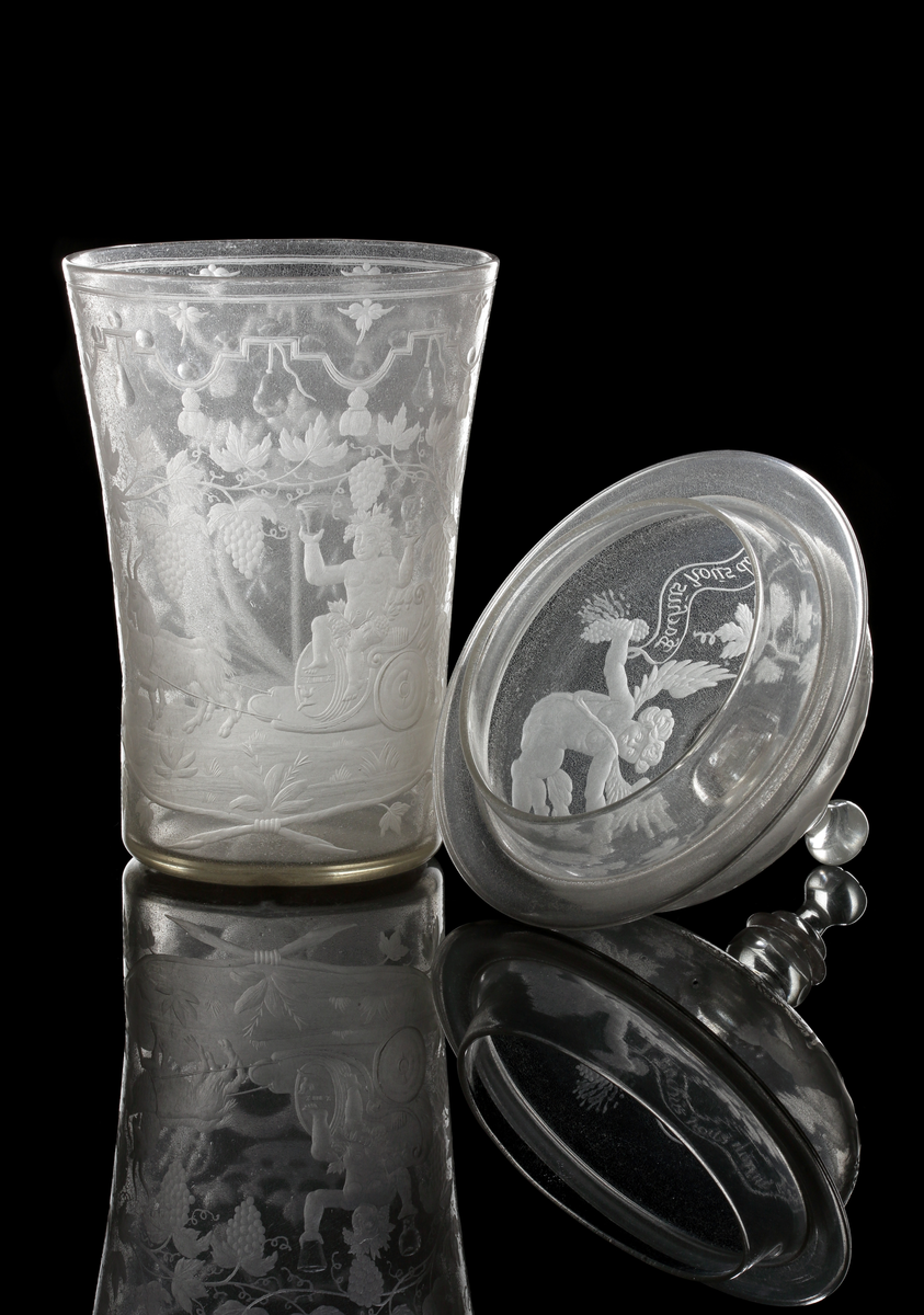 Bägare med lock. Svagt vidgande mot mynningen. Lock med profilared knopp som facettslipats.
Gravyr: Alliansvapen; syftar på greve Nils Gyllenstierna af Fogelvik (1648-1720) förmäld 1680 med Anna Christina Gyllenstierna af Björksund och Helgö (1657-1715). Bacchus dragen av två getter. På locket putti och text: "Le vien nous Menne a la gloire Bachus nous donne la victoire."
Inskrivet i huvudkatalogen 1936.