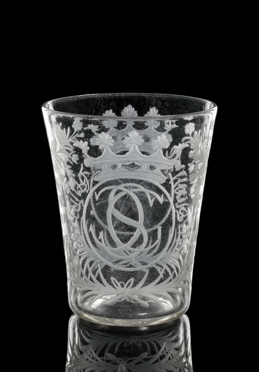 Bägare tillhör "Steningeservisen". 
Cylindrisk, vidgad uppåt. Graverad dekor: Blommönster. På ena sidan Gyllenstiernas monogram under grevlig krona med text runt om: "Häj luftig haisa vivat". På andra sidan: Gyllenstiernas vapen (sjustrålig stjärna) med text runt om: "Steninge 1705".
Följande text finns skriven i huvudkatalogen för M 9768 och vinglas M 9769:
Beskrivet av docent Heribert Seitz i brev till arkitekt P. Boberg av den 19 okt. 1937: "De härstammar från Gyllenstiernska godset Steninge (i Upland), ha alltid gått i arv och tillhört en Fru Bib Adelsköld. De äro fullkomligt unika. Den ofrånkomliga glassjukan har jag behandlat. Det gäller i främsta hand tre föremål."
Bägaren påminner närmast om figur 8:2, sid. 71, jfr plansch 25 C i min avhandling". (Seitz ?)
Inskrivet i huvudkatalogen 1937.