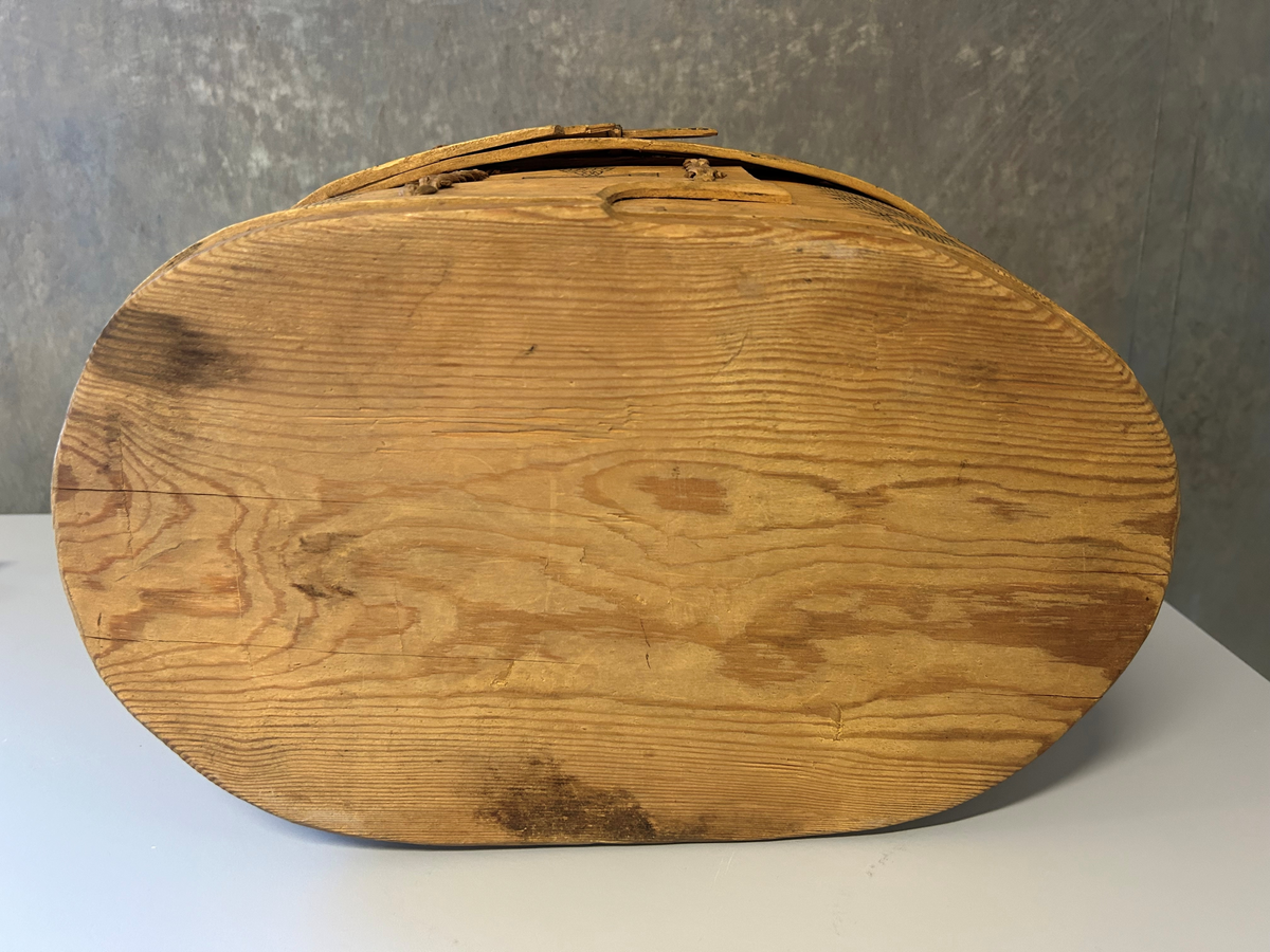 Oval bottenyta, ristad dekor med svart ifärgning. Lös botten.