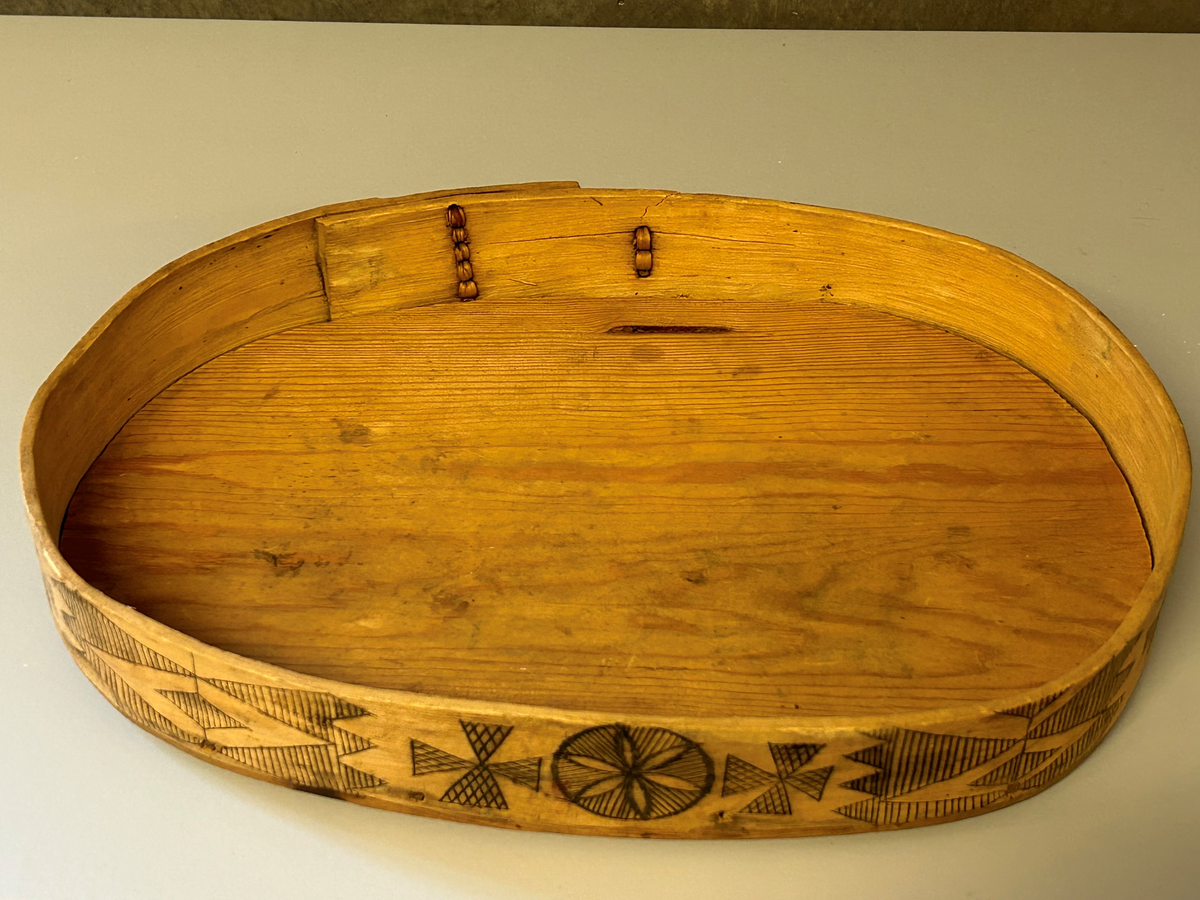 Oval bottenyta, ristad dekor med svart ifärgning. Lös botten.