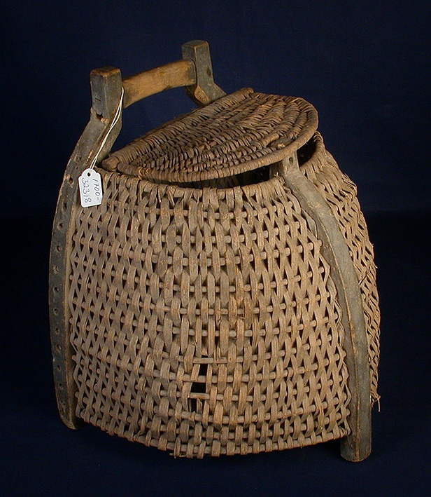 Korgen har en rundad form med platt baksida och är försett med lock. Korgen är uppbyggd av rotsträngar som är pluggade genom en hästskoformad ram på baksidan och en böjd träförstärkning på framsidans mitt. Vidjor är flätade mellan rotsträngarna. Även botten och lock flätade. Locket hålles på plats genom ett kvadratiskt hål på locket som läggs över trädelen på korgens mitt. Trädelen överskjuter korgens kant med 35 mm. Ramens övre ändar är sammanlänkade med en tvärslå som fungerar som handtag. Handtaget är fastsatt genom ändarna. Lockets bakre del är virat runt en träpinne. Vidjorna och rotsträngarna i locket är i storlek mindre och smalare. Ramen och förstärkningen på korgen är förlängda med 30 mm under korgens botten och bildar sålunda stöd eller fötter. Rester av ett rep finns på baksidan vilket visar att korgen kan bäras på ryggen.