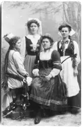 Vykort med ateljéporträtt av fyra kvinnor i folkdräkt. På ba