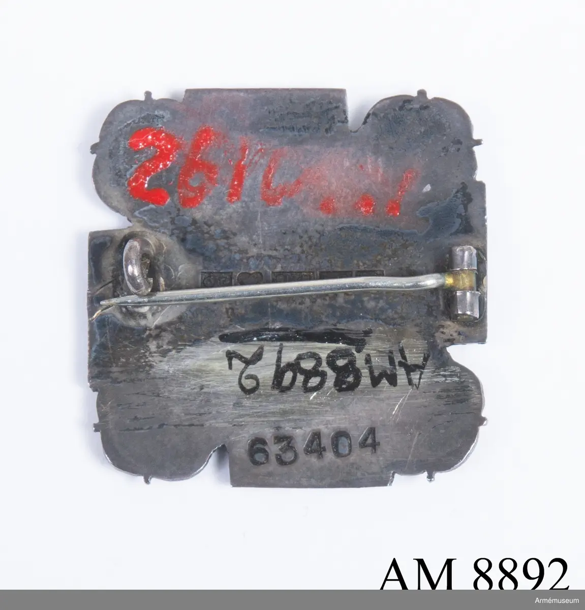 Av silver. Visar ett svastikakors i blå emalj med silverkant och namnet LOTTA-SVÄRD. Korset är omgivet av rosor i silver. Frånsidan bär silverstämplar och präglat nummer 63404.