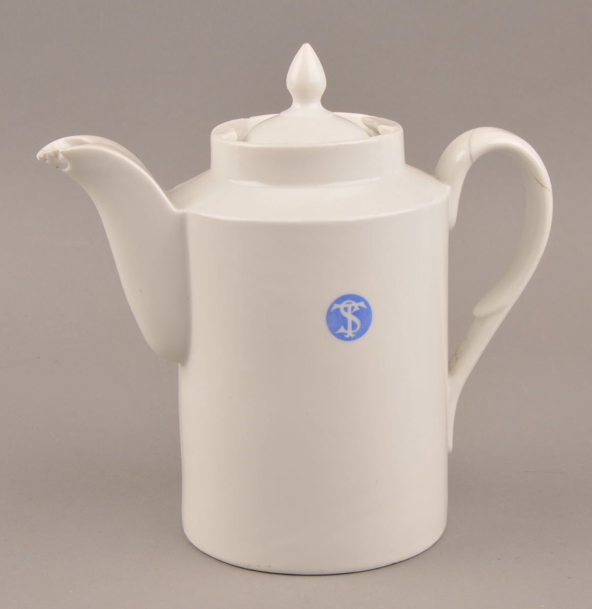 Kaffekanne i porselen, med inskripsjon til dampskipets selskap, - ST-logo begge sider
Firkanta fasong, med lokk nede i spor oppe på kanna, avspissa tut og spirforma knott på loket.
