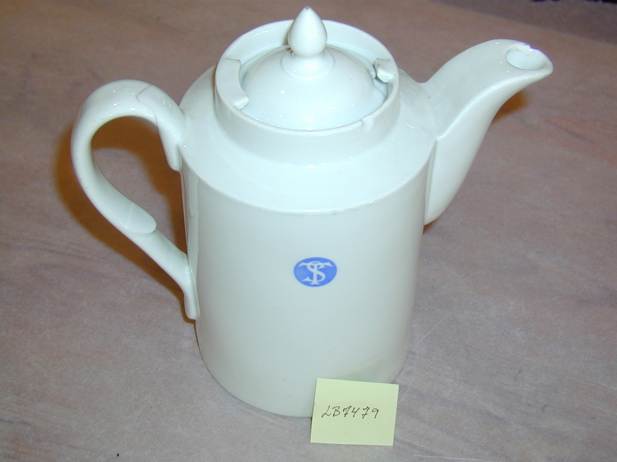 Kaffekanne i porselen, med inskripsjon til dampskipets selskap, - ST-logo begge sider
Firkanta fasong, med lokk nede i spor oppe på kanna, avspissa tut og spirforma knott på loket.
