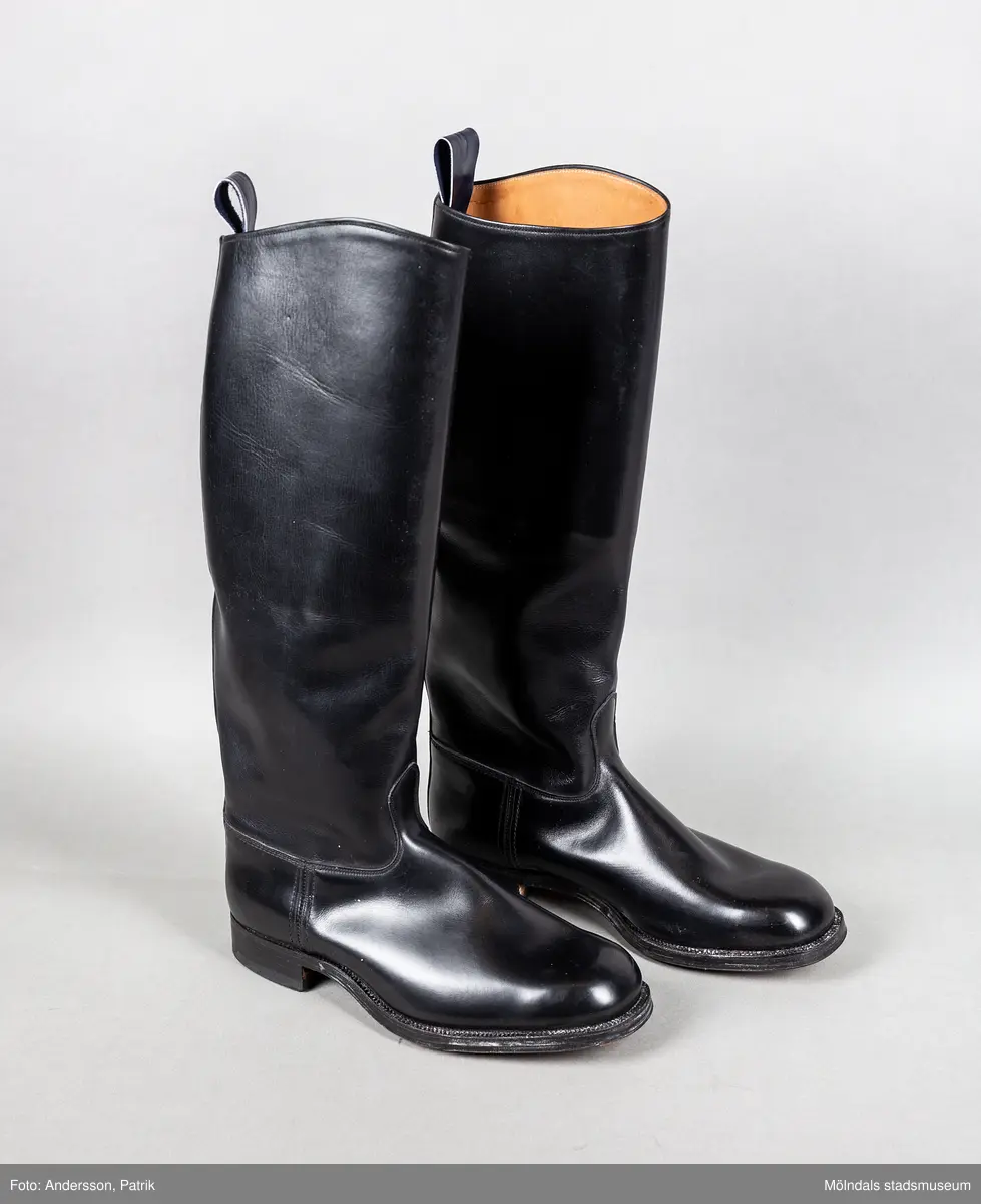 Ett par svarta ridstövlar i läder. Stövlarna är tillverkade på Ströms skofabrik i Kumla på 1950-talet och är mycket välgjorda. Dubbla sulor och handsydd randsula. Stövlarna har en flärp vid skaftets högsta punkt för att underlätta påklädning.  

Stövlarna hör till ridbyxor och härstammar från tidigt 50-tal.
Stövlarna tillhörde en flykting från Estland. Han flydde från Estland år 1944, under andra världskriget och var då 14 år gammal.
Stövlarna var tänkta att användas vid flykt, eftersom den tanken alltid fanns i bakhuvudet. Därför ville man vara väl förberedd med en för flykt passande klädsel. Kläderna kom aldrig till användning för det de var avsedda till.