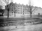 Vasavägen 12 stod under uppförande 1926. Den sammanbyggda huskroppen mot väster hade stått klar året före. Bägge husen gjordes lika och gavs stilenliga element hämtade från klassicismens formspråk. För ritningarna stod Axel Brunskog.