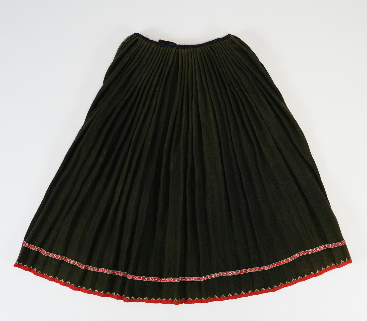 Stakk av grønn vadmel med grindvevd band og broderi langs skjørtekanten. Fangbredda er glatt med to folder i kvar side. Sydd av toskaft, påsett biter i blå krypertvevd vadmel. 

Stakken er sydd av fire høgder krypertvevd vadmel, fangbredden kjem i tillegg. 

Motfold midt bak, som i venstre "foldebunn". 19 folder på vestre og høgre side av motfolden. Avstand mellom foldletopen er 4.5-6 cm. 

