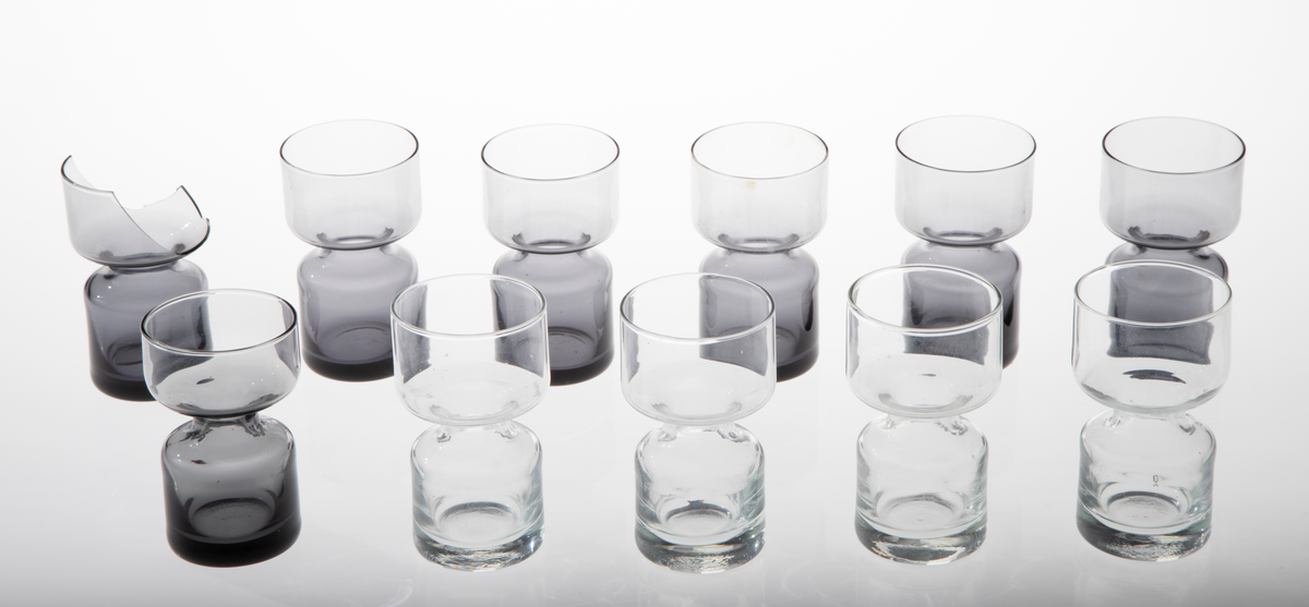 Elleve lysestaker i glass utformet som en sylinder som snevres inn på midten. Den øverste delen er litt videre enn den nederste. 

Fire lysestaker er i klart glass.
Sju lysestaker er i røykfarget, halvgjennomsiktig glass.