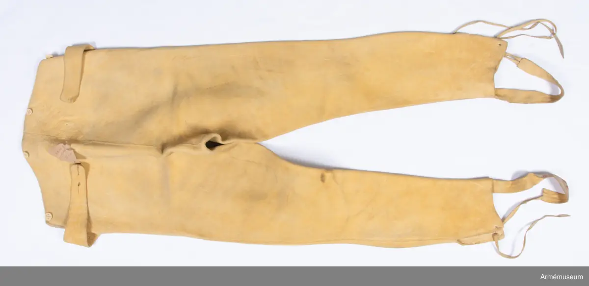 Gula skinnbyxor med knytband under foten.

Byxorna är sydda av gult sämskskinn med falsk smal lucka fram. Skinnet kan vara av älg, och är upp till 5 mm tjockt på vissa ställen.
Två stolpar som ska härma sidöpningarna på en lucka är applicerade ovanpå framstycket, och nedsytt med stickningar. I varje sida av den stora luckan sitter en spänntamp av skinn avsedd att knäppas ihop i ryggen.
Den egentliga öppningen är i sidorna där luckan stängs med stora knappar. Byxorna är konstruerade med två fram- och två bakstycken. De är ofodrade, men har infodringar i linningen och luckan av tunnt skinn i samma färg, samt vid alla punkter där plagget utsätts för extra slitage.
Nertill i varje bens utsida finns en ca 11-12 cm hög slits samt en hälla fastsatt för att fästas under foten. Hällan är av samma skinn som byxorna, och förstärkt med ett vävt röd och vitrandigt band. De vita trådarna i bandet är troligen av lin, medan de röda (som nästan är bortnötta) ser ut att vara av ull. I änden av varje hälla sitter två skinnremmar för snörning i sydda snörhål på motsatt sida vid slitsen.
Knapparna är av ben och i två storlekar. En stor sitter i varje sida av luckan, medan 2 små fram och bak troligen är till för fastsättning av hängslen. Knapp saknas i spänntampen bak. Knapphålen i luckan är passpoalerade.
Byxornas linning är kantad med passpoal av skinn.
Hela plagget är troligen färgat efter sömnad, för man kan se att lintråden som man har sytt alla sömmar med också är gul.
Sömnadsarbetet är mycket skickligt utfört, och samtliga delsömmar pryds med en stickning på varje sida.