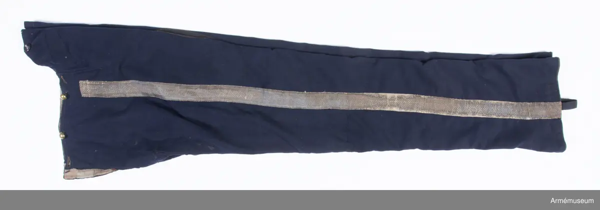 Mörkblå långbyxor med skinnskoning i baken och på benens insida, samt revärer av metallgalon i sidorna.

Byxorna är sydda av mörkblått kläde och har 4 cm breda revärer av silvergalon på benens utsidor. De är ursprungligen av en äldre modell med hel lucka fram, men har sytts om till gylf mitt fram, troligen i samband med att gylf fastställdes för långbyxor 1845. I varje sida syns spår efter luckan i form av ett smalt insnitt, samt ett igensytt knapphål.
Gylfen har dold knäppning med 4 enkla svartlackade knappar.
Byxorna är skinnskodda med brunt skinn i baken och på benens insidor, men det syns även rester efter en rad stygn ovanför knät på båda ben som eventuellt kan vara spår efter en äldre skinnskoning.
Byxorna är ofodrade, men har en infodring av oblekt bomullstyg i linningen upptill och en bit ner på framstycket. Infodringen är lappad på flera ställen.
På vänster byxben vid knät syns en stor lagad reva i tyget. Nertill vid fållen sitter i vänster byxben en sekundär hälla av svart resårband, samt en sekundär svart plastknapp. Dessa har troligen satts dit i samband med att byxorna varit utställda.
På insidan av höger bens fåll sitter två små knappar för fastsättning av hälla. En lapp eller lagning är dessutom iskarvad vid höger knä.
Byxorna har 3 knappar bak och 4 fram för fastsättning av hängslen. De två knapparna på höger sida fram är kullriga mässingsknappar, medan övriga är 4-hålsknappar av svartlackad metall.