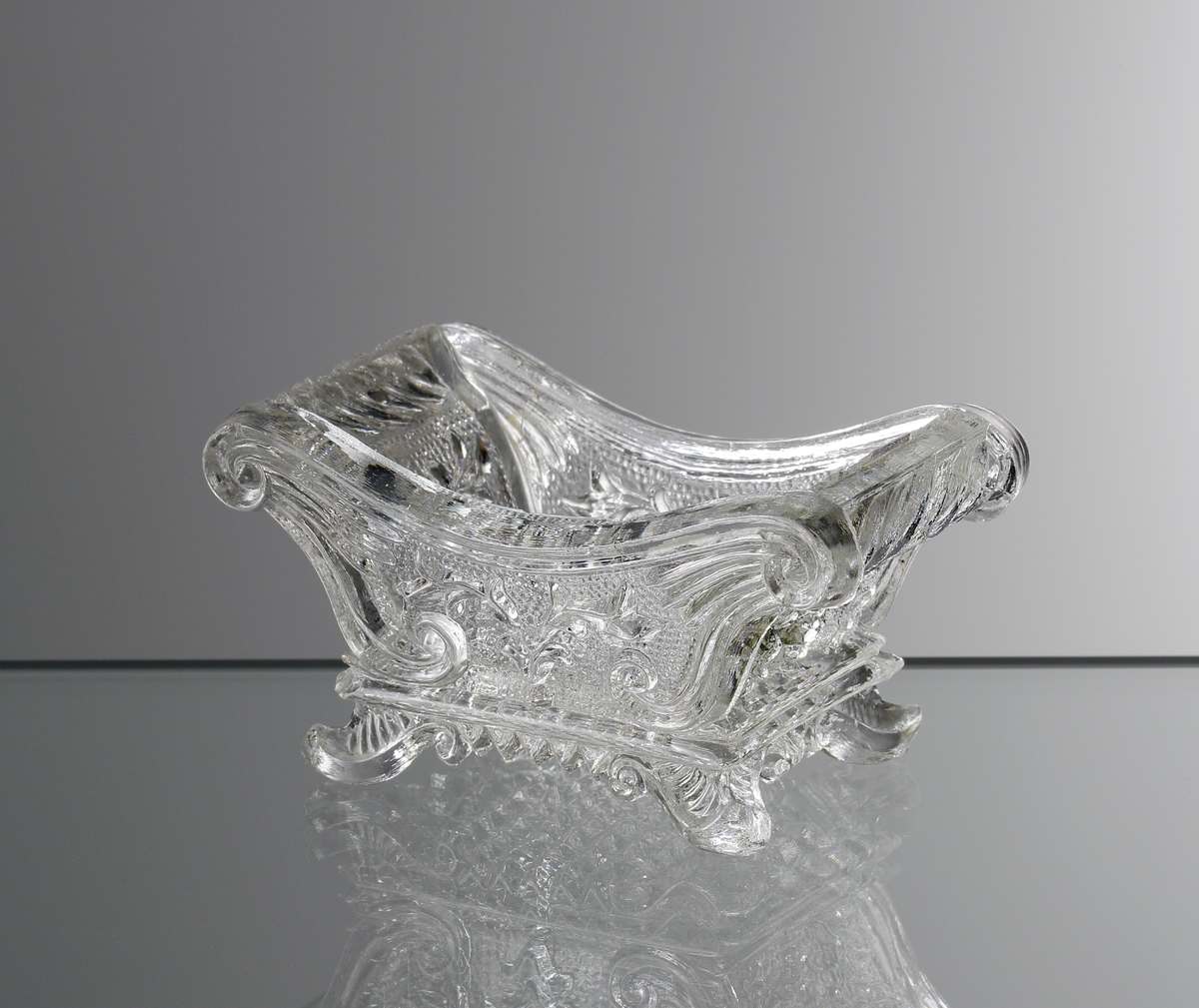 Saltkar. 
Tillverkat på Bostorps glasbruk. Många formar från Bostorp hamnade på Gullaskrufs glasbrulk efter nedläggningen.
Blomstermotiv och ruta.
Ofärgat klarglas.

Inskrivet i huvudkatalogen 1935.