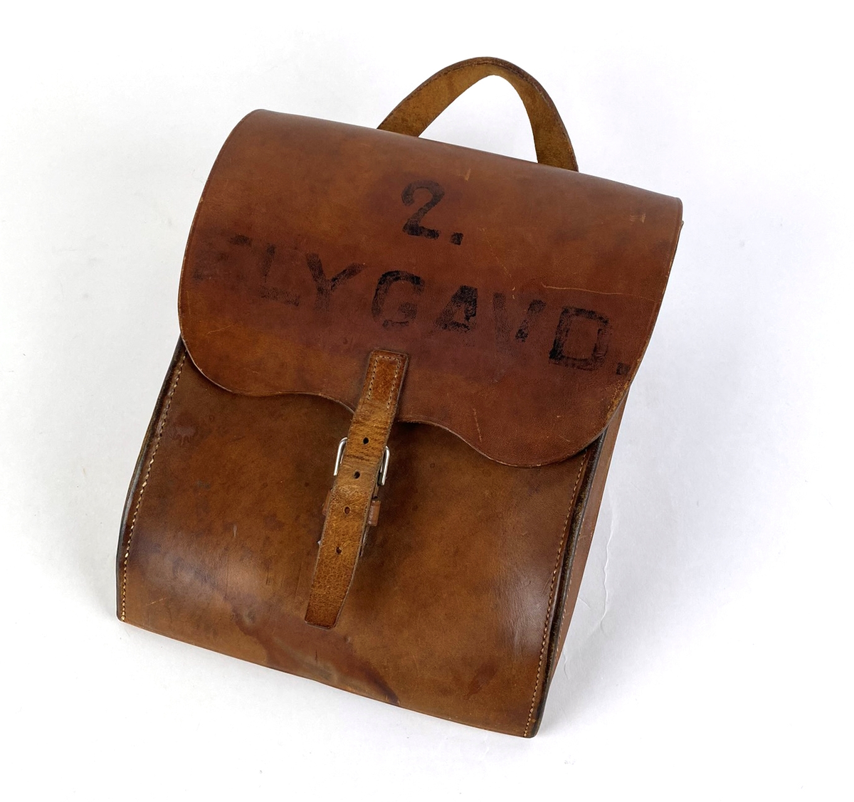 Läderväska med bärhandtag och ett läderspänne. I väskan finns hållare för pennor eller verktyg. På locket finns målad text: "2. FLYGAVD."