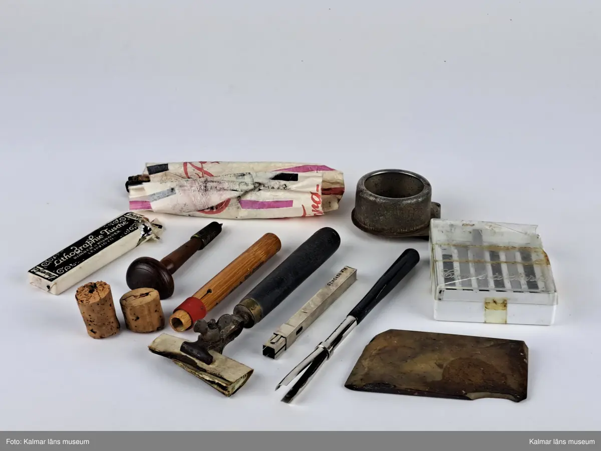 KLM 46734:25. Konstnärsmaterial, samling. En samling måleritillbehör, varav en del förvarat i askar med lock, bestående av två flaskor lack i förpackning, fyra flaskor nejlikolja, tre etsningskulor i förpackning, pennor, ritkol, olika knivar och palettknivar, sudd, stompfer, palettkopp, pappersremsor, stålstift till pennor, vinkelhake samt andra typer av redskap.